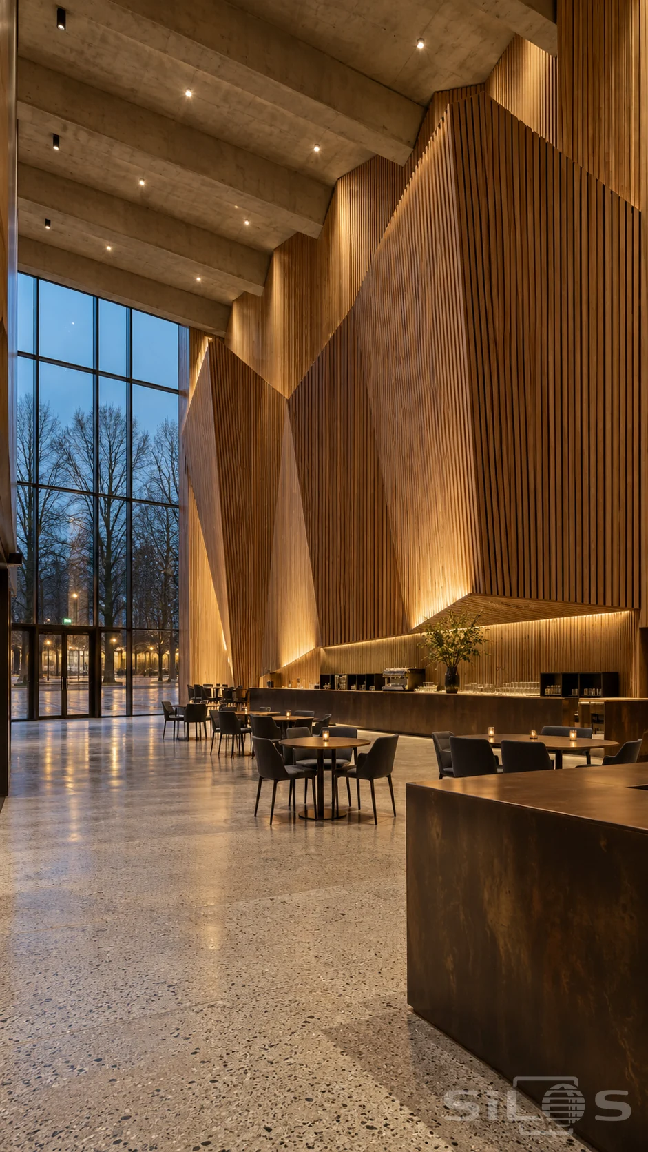Empty concert foyer with a huge angular oak slat wall, concrete roof beams, bronze counter, small tables and tall windows at blue hour.