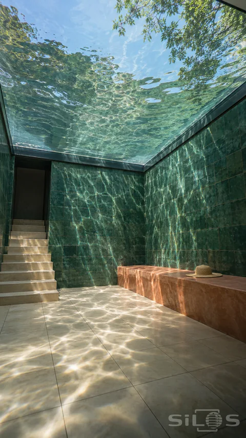 Water ceiling room with green tiled walls, dry cream flooring, an access stair and a terracotta bench beneath rippled glass.