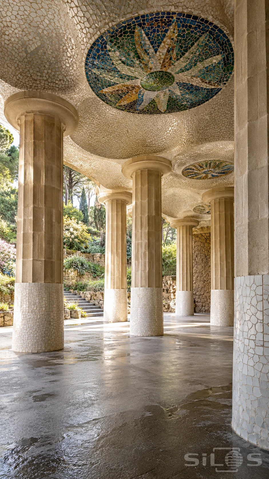 Fluted stone columns support an undulating ivory mosaic ceiling with blue, green and amber medallions above damp paving.