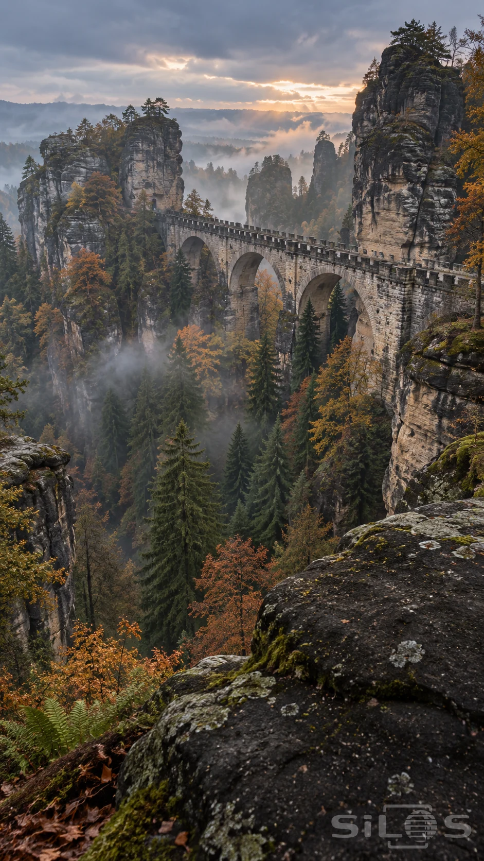 A sandstone gorge bridge links tall rock formations above a forested valley.