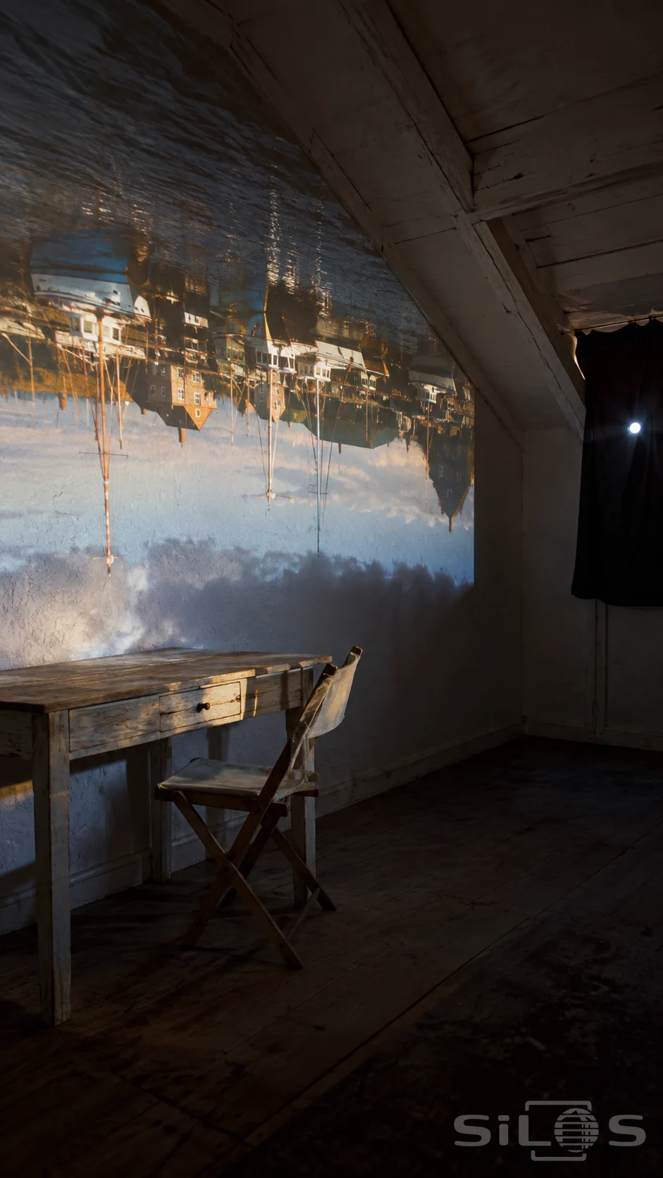 A camera obscura room with an upside-down harbor projected across pale attic walls and simple furniture beside a darkened window.