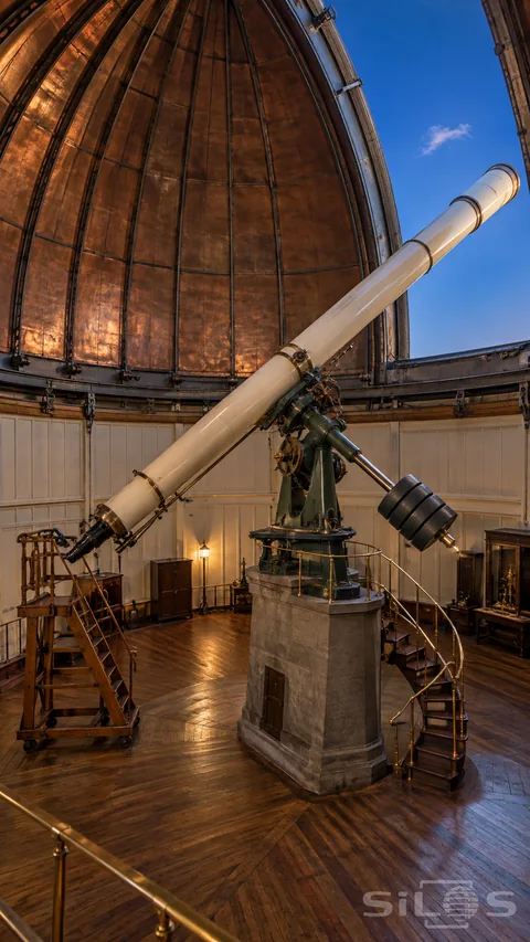 Observatory telescope on a stone pier beneath an open copper dome; with brass rails; a stair and a wooden observing ladder.