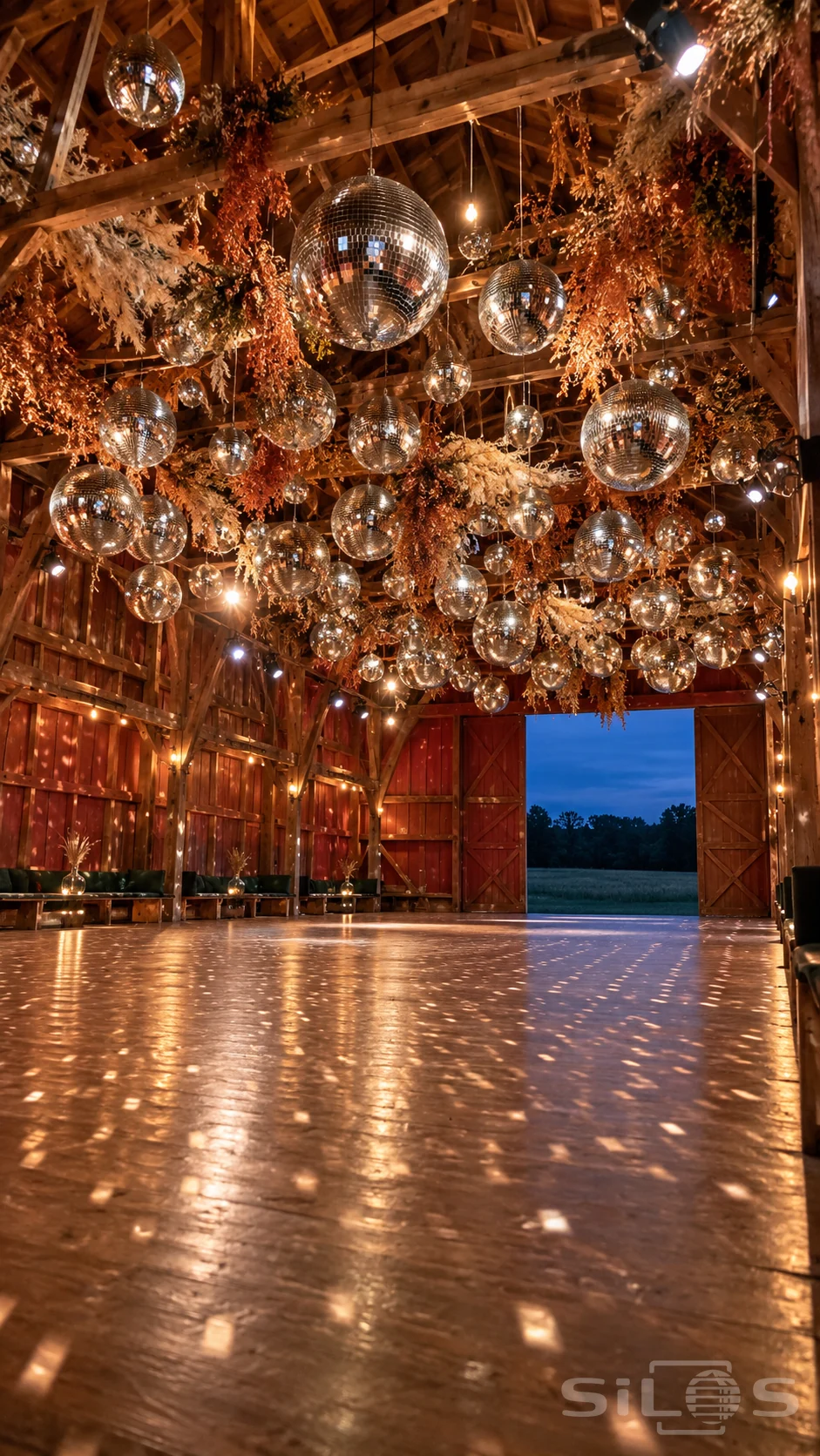 A mirror ball cloud hangs among copper foliage above an empty timber barn dance floor in warm evening light.