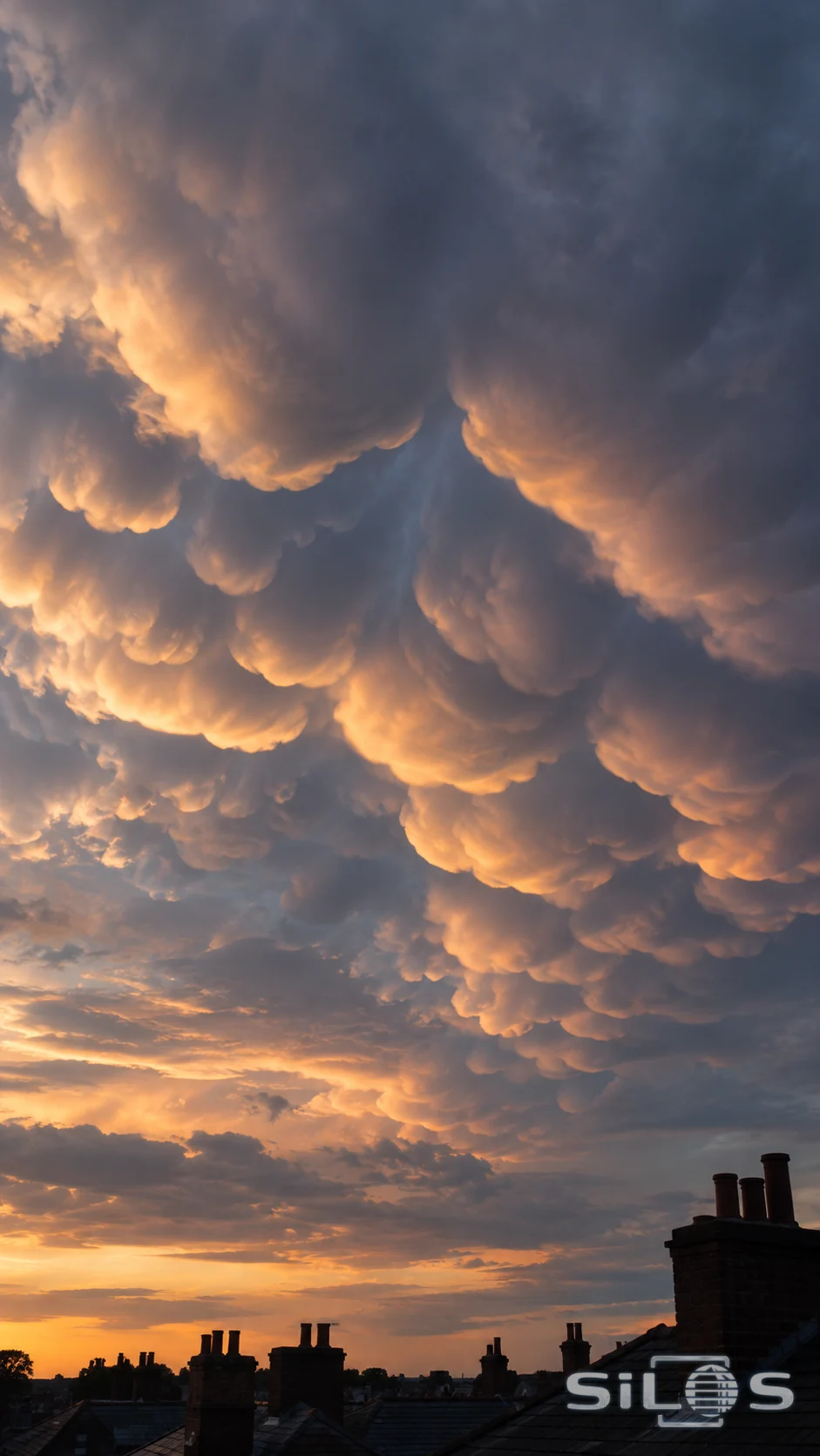 Rounded storm-cloud lobes catch pale light above quiet rooftops