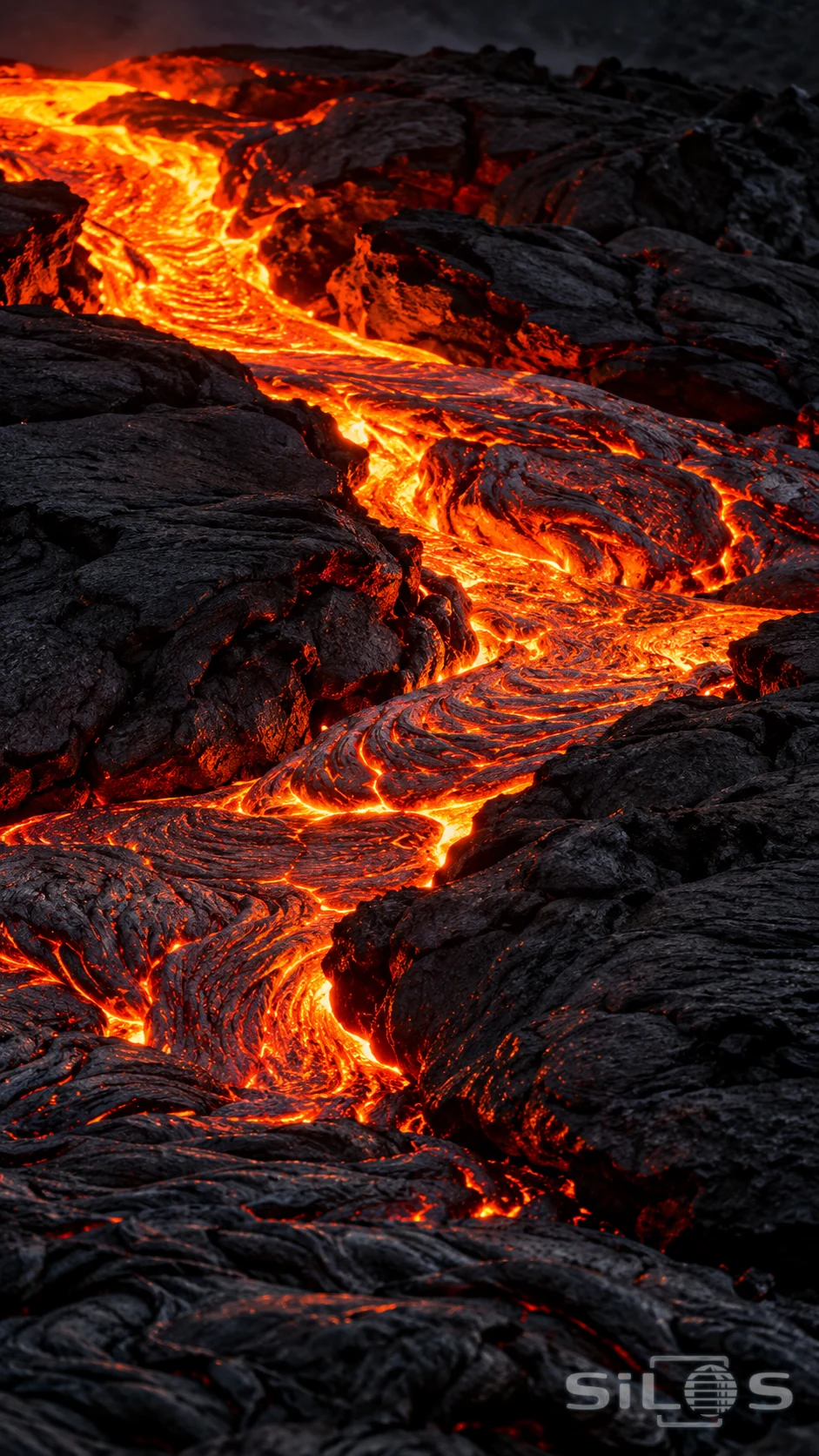 A narrow ribbon of glowing lava passes between rough black volcanic stone