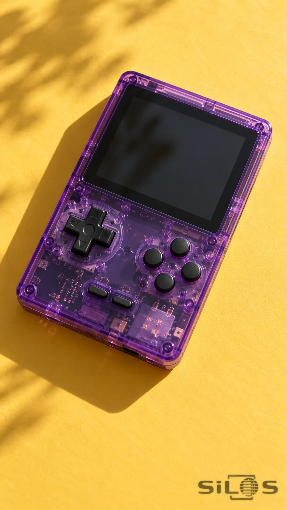 An unbranded translucent purple handheld game console with a blank screen, dark controls and visible internal components on a yellow surface.
